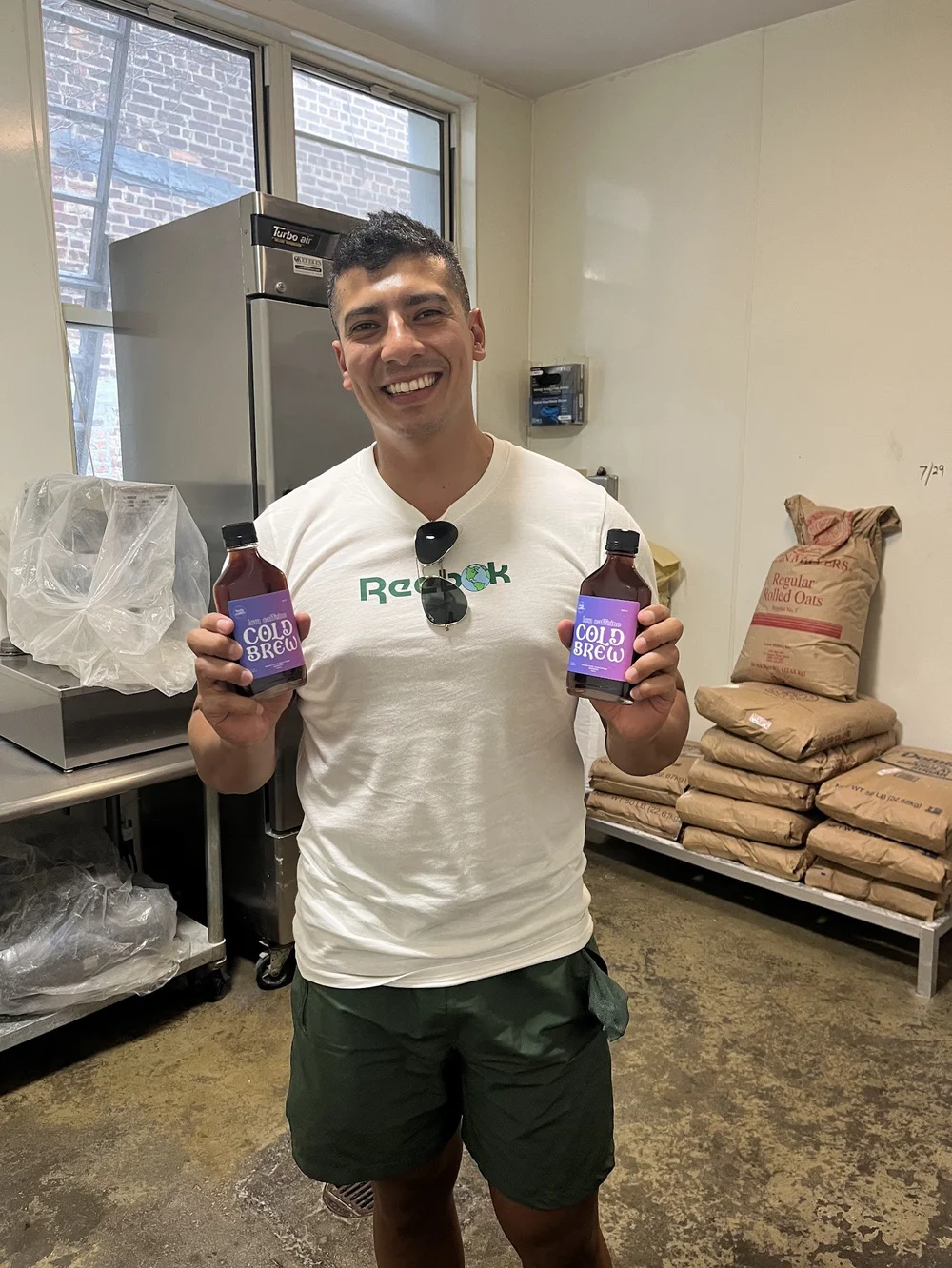 Man holding two bottles in a commercial kitchen
