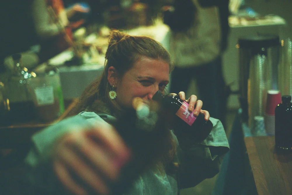 Woman drinking cold brew at an event, film photo