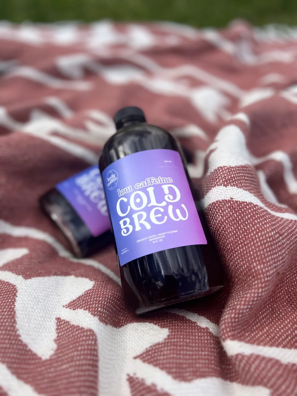 Bottle of cold brew resting on a picnic blanket