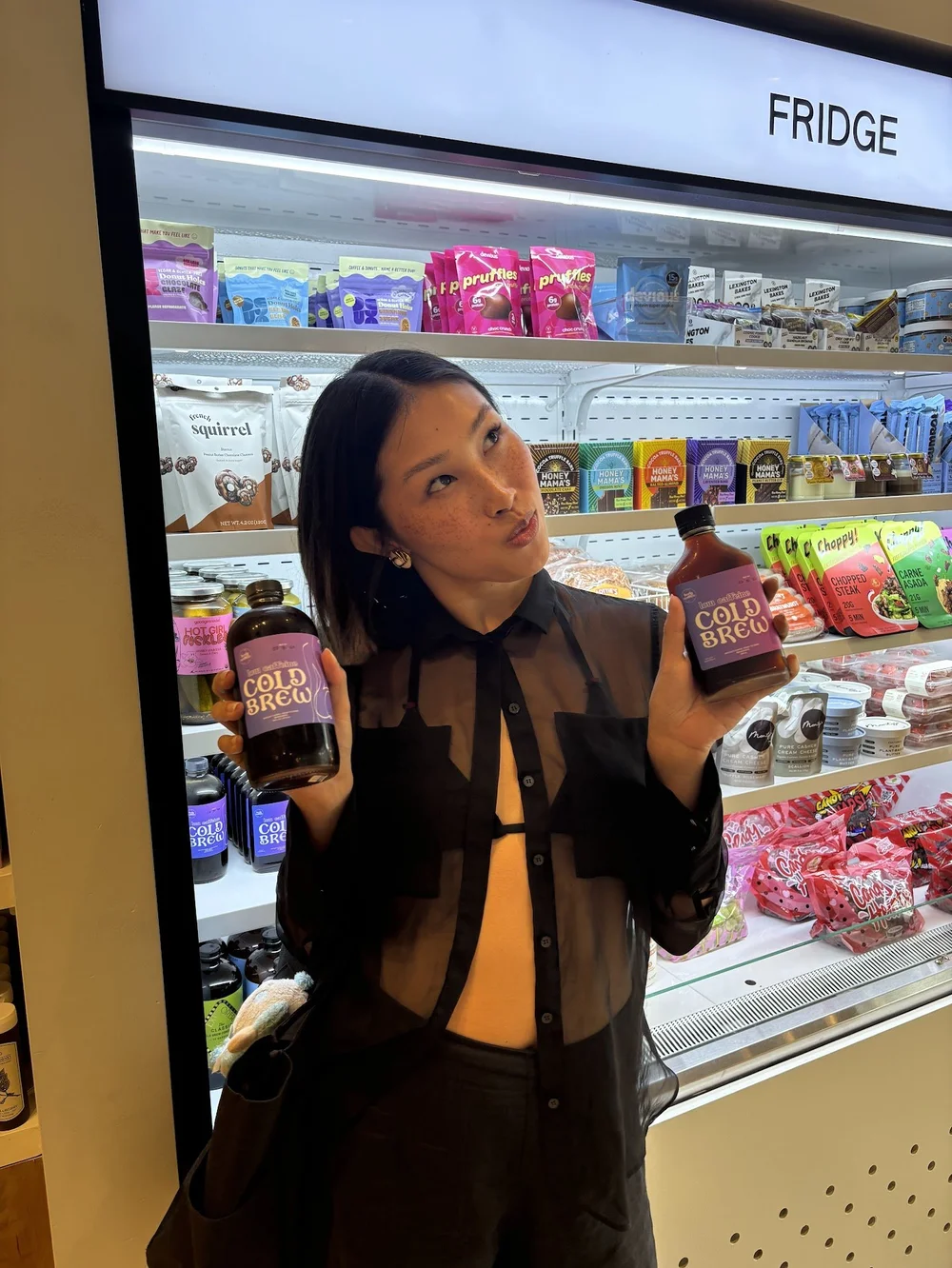 Woman posing with bottles at a Pop Up Grocer fridge